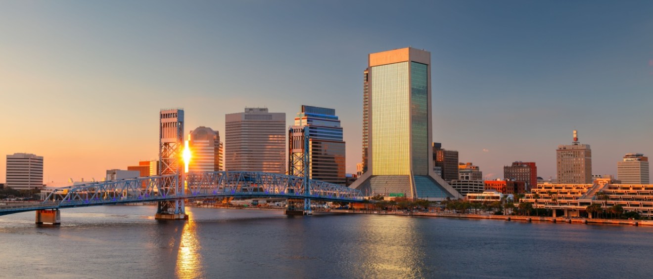 A scenic sunset view of Jacksonville showcases the city skyline reflecting beautifully on the water. This picturesque moment contrasts with the practical concerns many consider when relocating, such as the cost of living in Jacksonville, which remains one of the more affordable options among major U.S. cities.