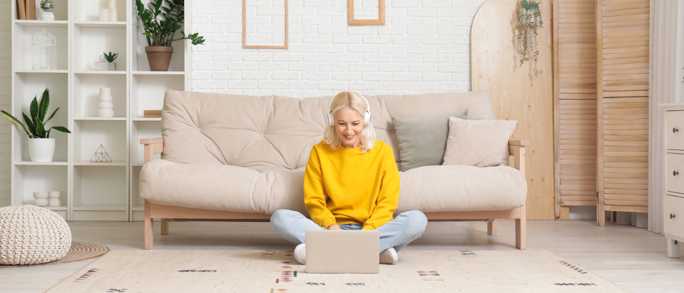 Woman renting alone researches neighborhoods on her laptop in a cozy apartment living room.