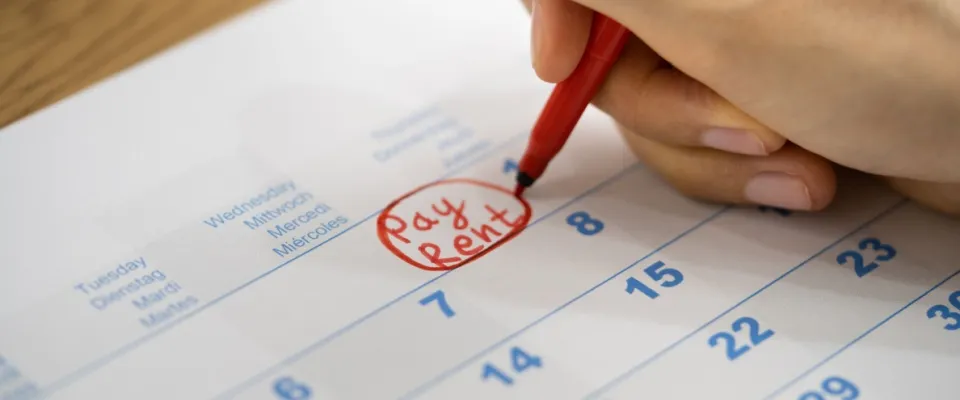 A close-up of a hand circling a rent due date on a calendar with a red marker, visually illustrating the concept of flexible rent payment options and how renters can better manage their monthly costs.