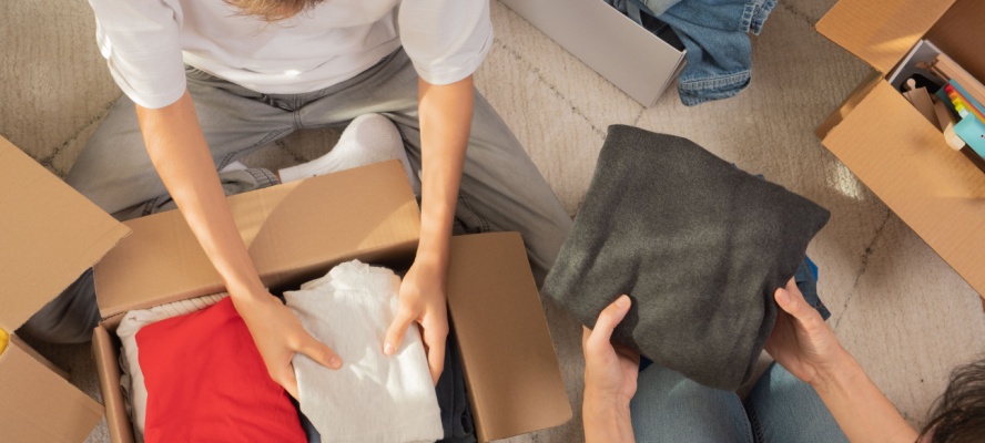 Woman and child sorting clothes and packing into cardboard box to be put in storage in Tallahassee