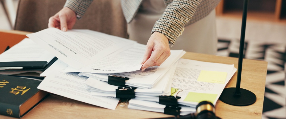 Hands sorting a stack of legal documents in an office, ready for review or inspection — an important step in the move-out procedure.