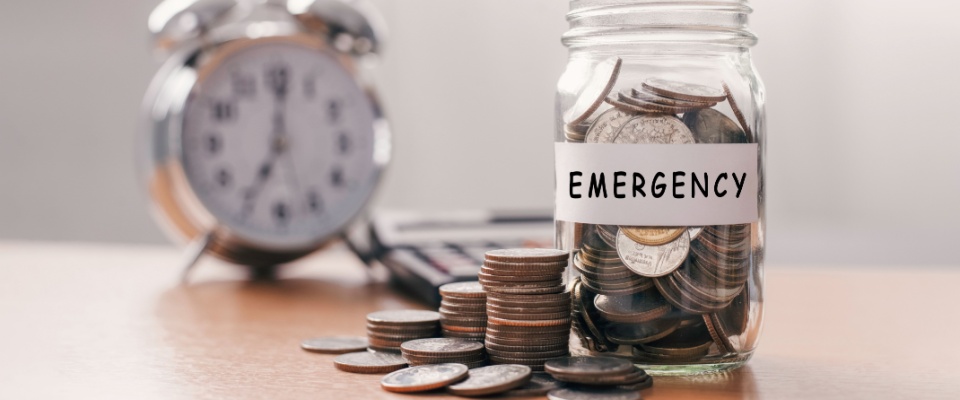 A glass jar filled with coins sits beside a piggy bank, symbolizing financial preparation and smart budgeting — essential habits for those managing expenses in a multi-generational household.
