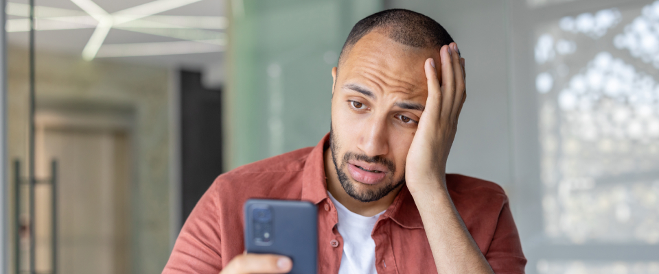 A frustrated person looking at their phone while trying to learn how to cancel their apartment application.