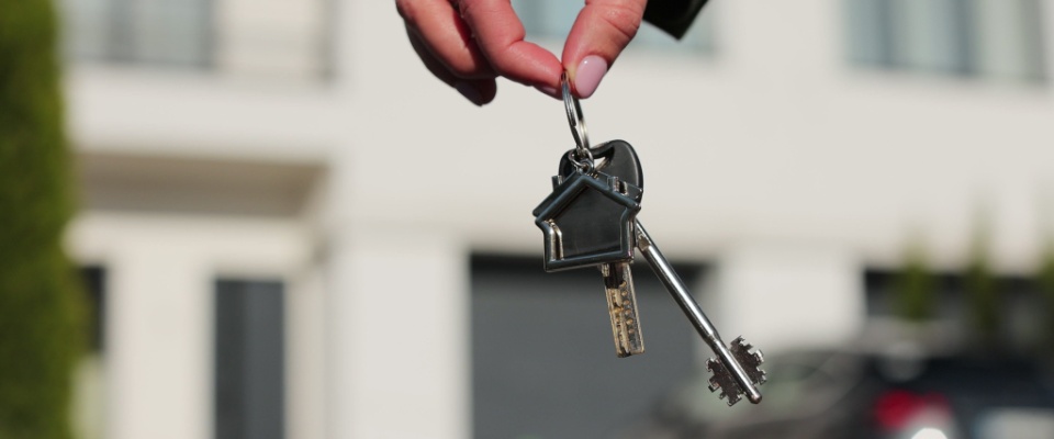 Close-up of a house key in a woman’s hand, symbolizing an important milestone in the move-out procedure.