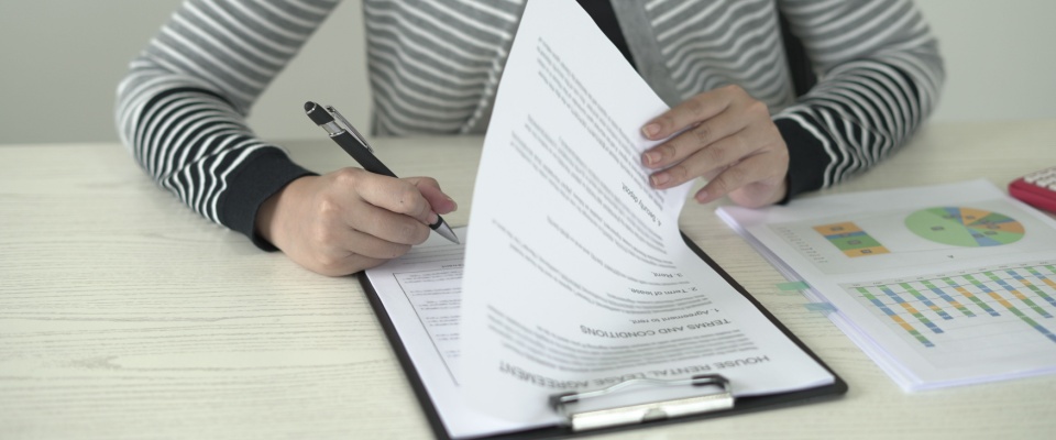 A real estate agent reviews and signs rental contract documents while working remotely — a glimpse into professional responsibilities managed from a multi-generational household, blending career and family life under one roof.