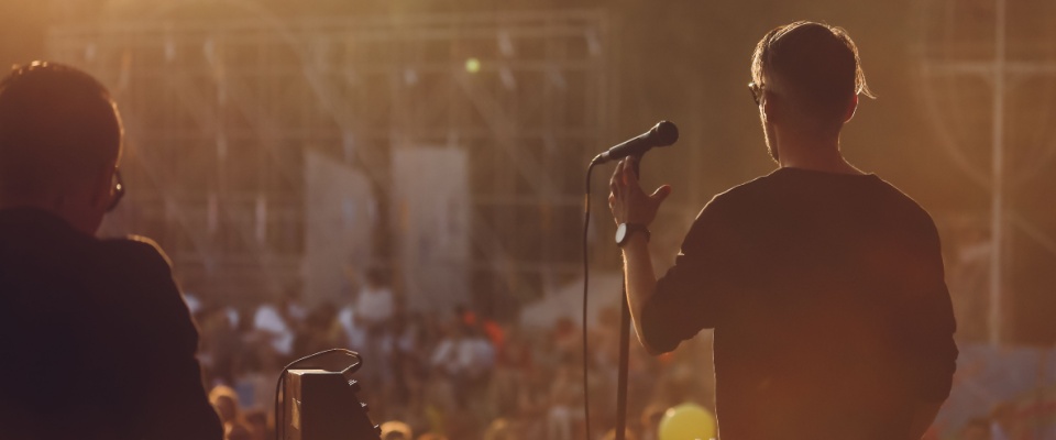 A singer performs on stage at a lively summer outdoor music festival, energizing the crowd under the warm sun—capturing the vibrant cultural scene that enhances the appeal of apartments in Cincinnati.