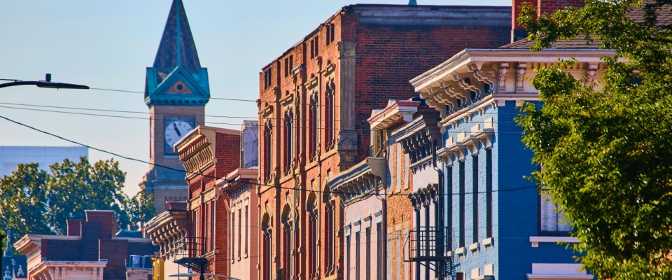 Charming colorful historic buildings and a clock tower line a picturesque street in Cincinnati, reflecting the city's unique architectural heritage and vibrant community atmosphere—appealing qualities for those seeking apartments in Cincinnati.