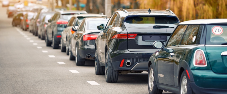 Rows of cars tightly lined along a narrow residential street highlight common parking questions, from limited free space to overcrowded public parking zones in busy neighborhoods.