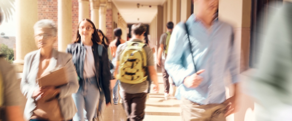 A bustling university campus with students heading to class captures the vibrant atmosphere of moving near a college town, where education and community life intersect.