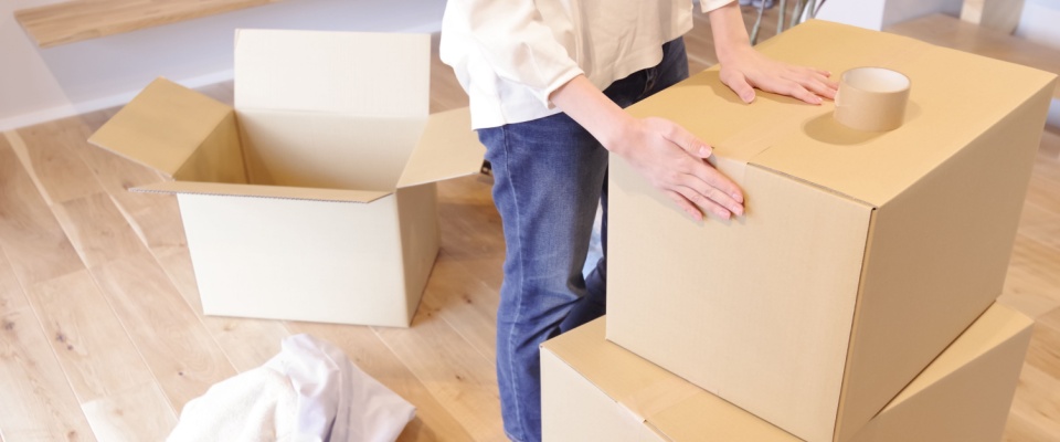 Woman packing her belongings into a cardboard box, illustrating an essential step in the move-out procedure.