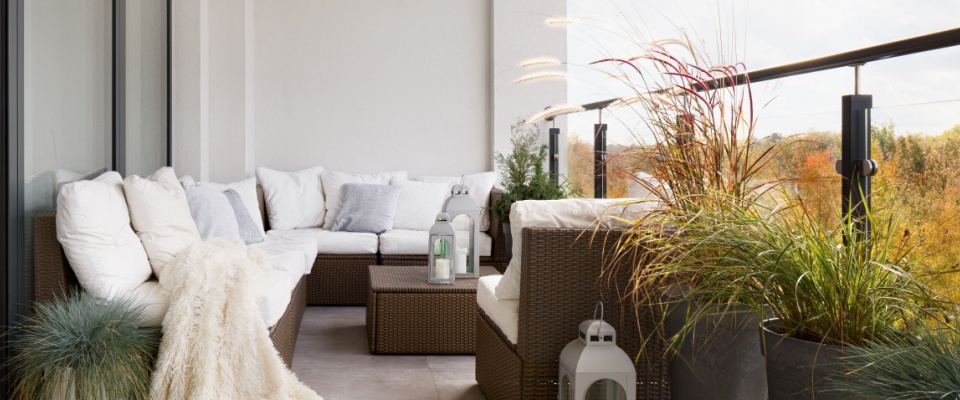 Spacious balcony with comfortable seating, plush cushions, decorative lanterns, and potted grasses, demonstrating balcony etiquette by maintaining a safe, neat outdoor space.