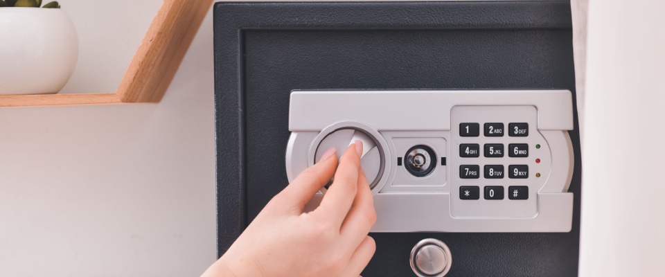 A close-up of a hand turning the dial on a secure digital safe, visually emphasizing the importance of protecting high-value items.