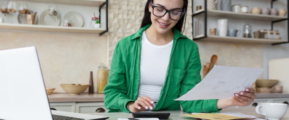 A young woman smiling as she reads a banking notice about her final mortgage payment. For renters, moments like this often begin with the lease commencement date, which sets the timeline for budgeting, payments, and financial planning.