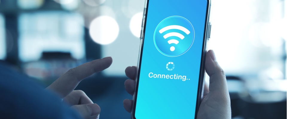 Person holding a smartphone with a wireless connection screen, emphasizing the importance of securing Wi-Fi networks to protect against identity theft.