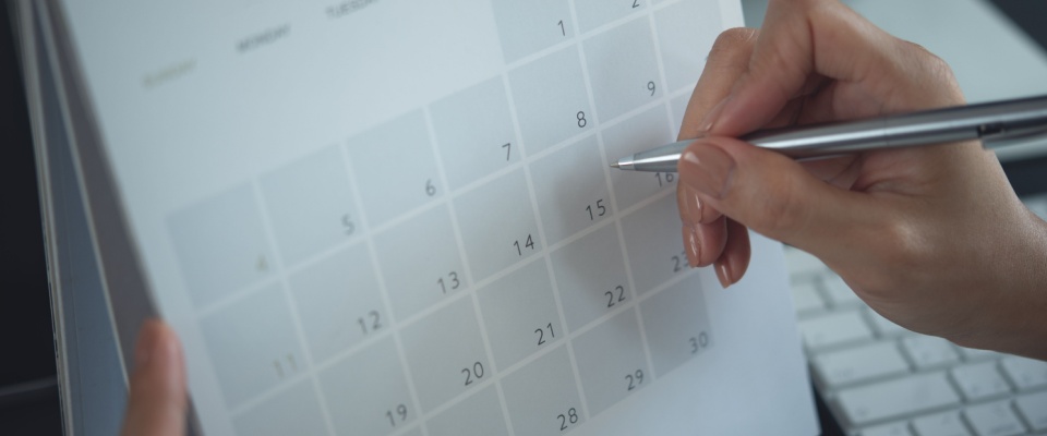 A close-up of a woman writing in a planner to organize her schedule and set important dates. This scene connects to the lease commencement date, a key calendar event marking the official start of a rental agreement.