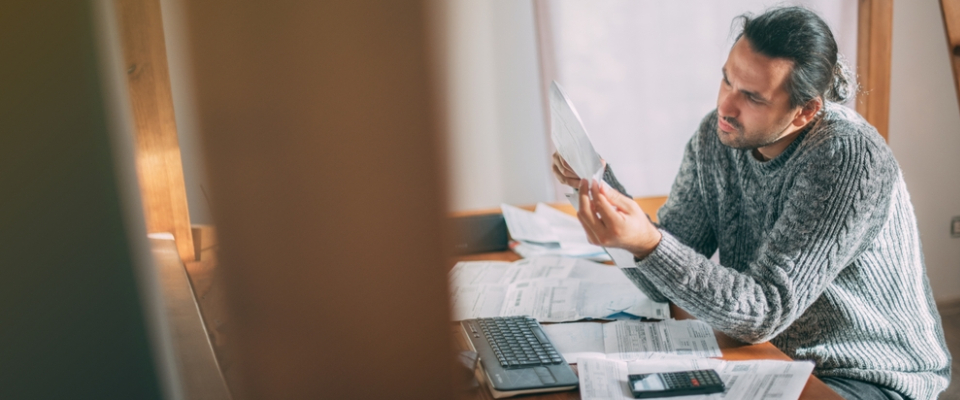 Renter reviewing bills and paperwork at home, illustrating the importance of understanding extra costs beyond base rent when leasing apartments in the Bronx, NY.