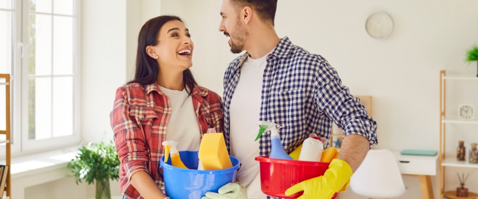 A cheerful couple cleaning their living room together, demonstrating teamwork and shared household duties — a great example of cooperation often outlined in a roommate agreement.
