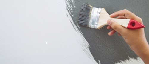 Hand painting a wall gray, symbolizing lead-based paint disclosure and the importance of renter awareness in older apartments.