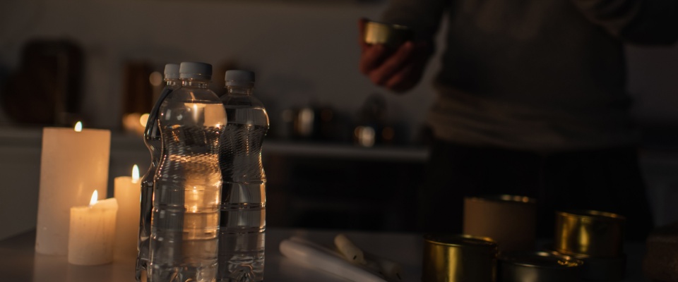 A reserve of bottled water, canned food, and candles in a dim kitchen — a reminder of preparedness and planning when considering long-term living options such as apartments in Las Vegas.