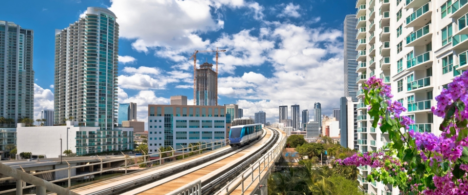 Miami Metromover train traveling through downtown high-rise apartments, showcasing public transit in Miami as a convenient option for renters seeking easy commutes and car-free living.