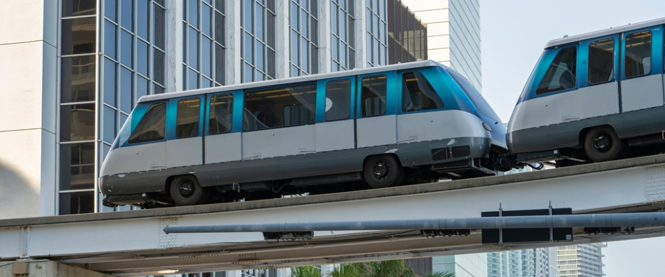 Close-up view of Miami’s elevated Metromover cars traveling on the guideway with downtown office buildings in the background.