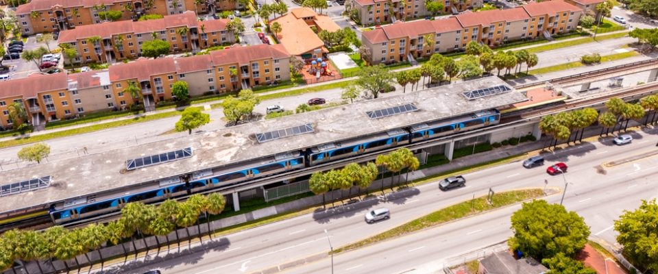 Aerial view of a Tri-Rail commuter train at a Miami station near residential apartments, highlighting public transit in Miami as a practical choice for renters.