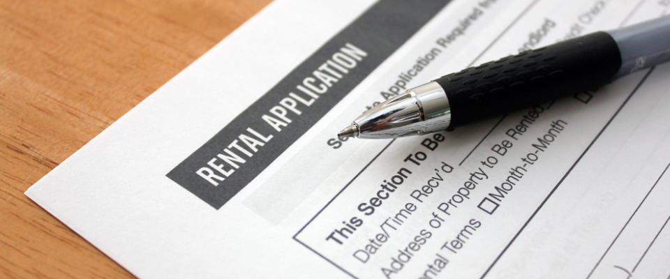 Close-up of a rental application form with a pen on top, representing paperwork and preparation needed for apartment hunting in competitive rental markets.