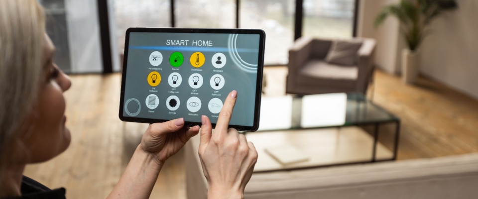A woman using a digital tablet to adjust her smart home air conditioning, showcasing energy efficiency and modern technology available in apartments in Las Vegas.