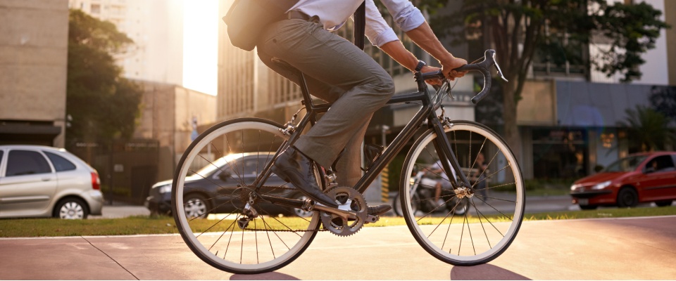 A businessman rides his bike through the city on Baltimore public transit routes, embracing a sustainable and carbon-neutral way to commute in the morning.