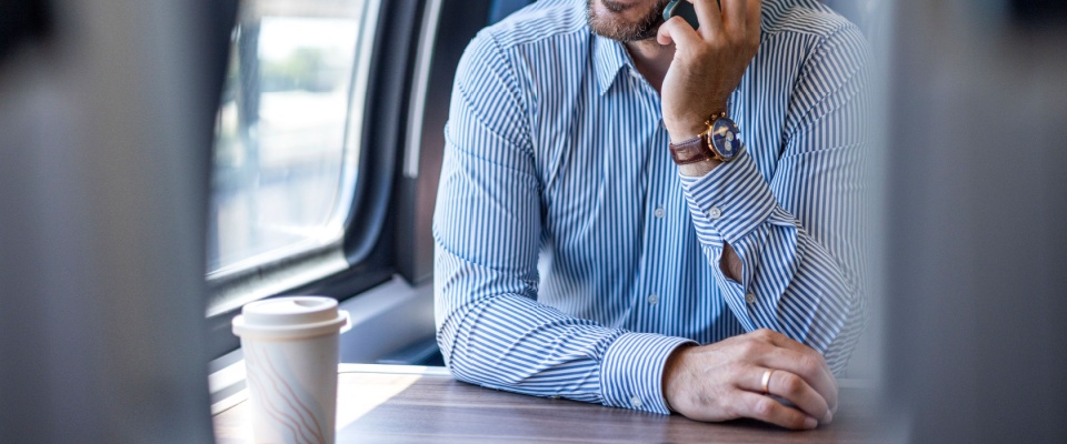 A young professional uses his smartphone while commuting on Baltimore public transit, blending work and travel during his daily train ride.