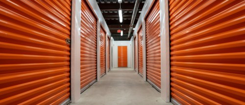 Empty hallway with orange garage doors of a self storage unit