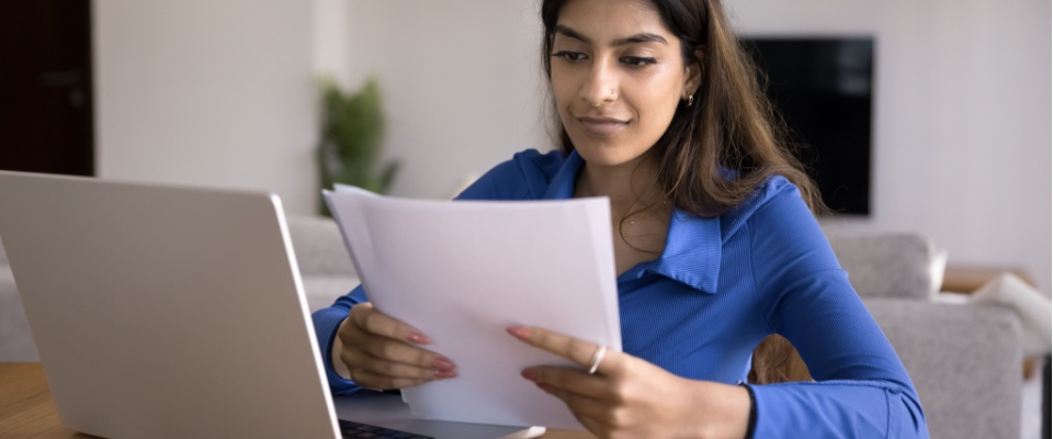 Woman reviewing renters insurance documents at home, learning how to prevent an apartment from becoming uninhabitable.