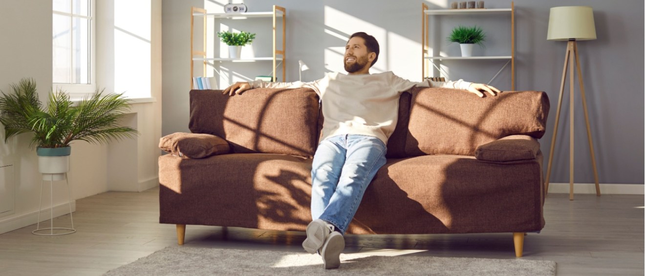 Man sitting comfortably in a well-maintained apartment, representing the importance of repairs to avoid uninhabitable conditions.