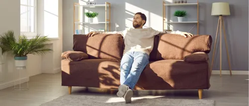 Man sitting comfortably in a well-maintained apartment, representing the importance of repairs to avoid uninhabitable conditions.