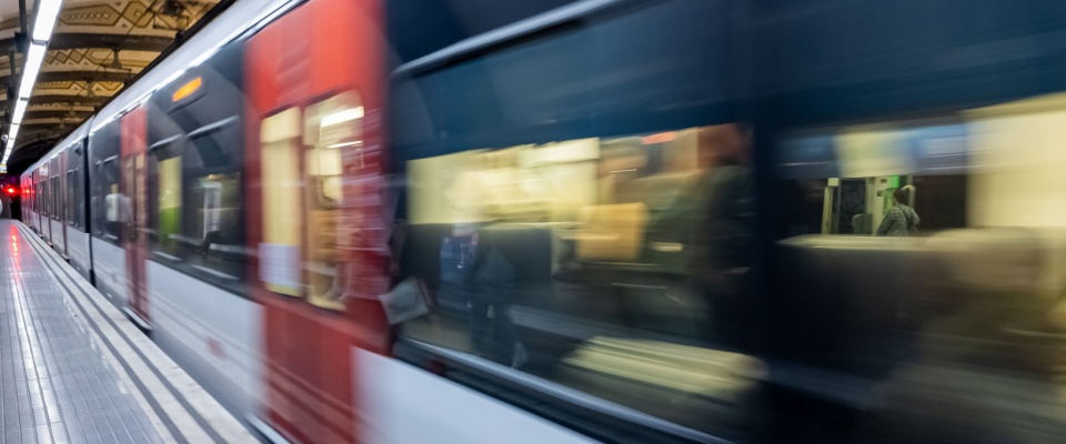 A blurred train speeding past an urban station platform captures the dynamic pace and energy of daily life on Baltimore public transit.