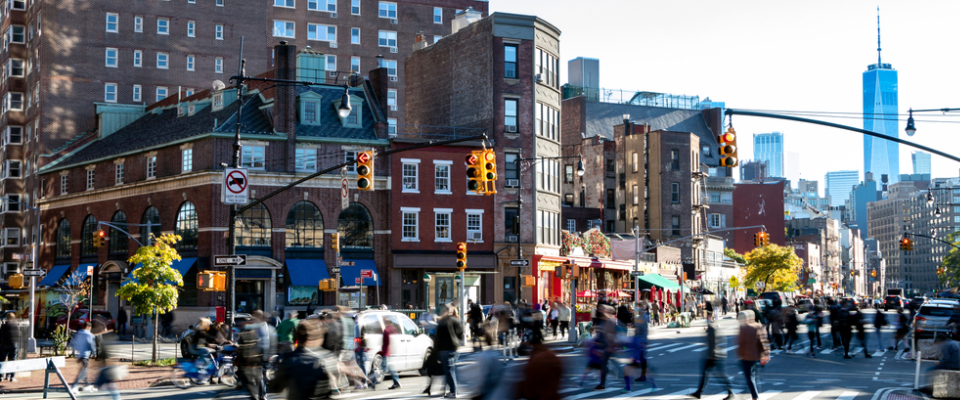 Busy downtown New York City street with pedestrians, traffic, and apartment buildings, showing the lively atmosphere near downtown apartments.