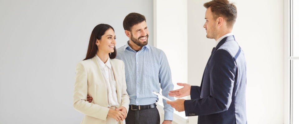 A family couple discussing options with a realtor in a bright new home, illustrating the negotiation and paperwork process that can accompany a lease break or new rental agreement.
