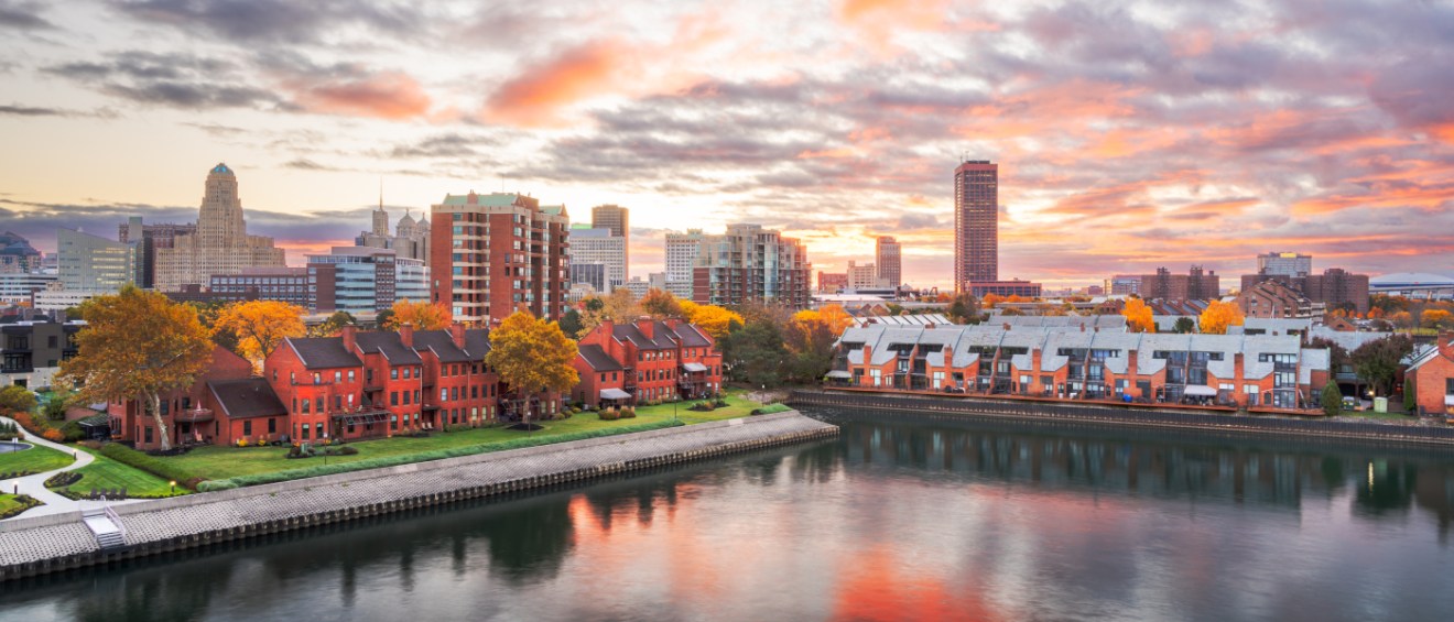 Scenic view of downtown Buffalo, NY at sunset with apartments along the waterfront, illustrating the housing and cost of living in Buffalo.