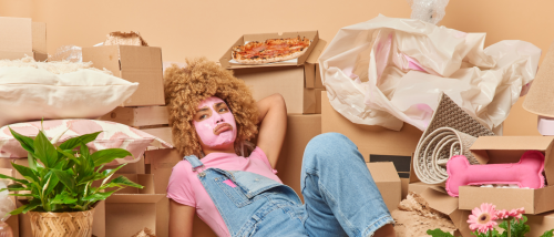 A person wearing a face mask, surrounded by boxes full of their stuff, wondering how to rent after an eviction.