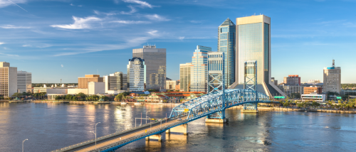 A sunny view of downtown Jacksonville, Florida, featuring the blue Main Street Bridge over the St. Johns River — highlighting the city’s accessible neighborhoods and convenient public transit options for renters.