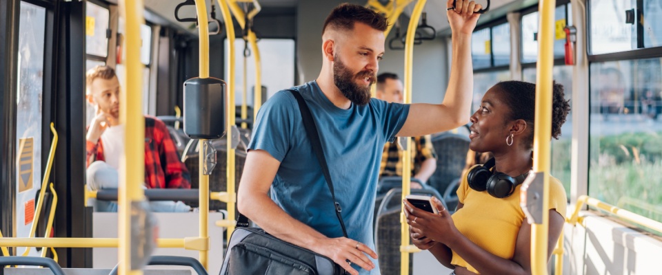 Cheerful diverse friends chatting and using a smartphone while commuting by bus, showcasing the friendly and connected atmosphere of Milwaukee public transit.