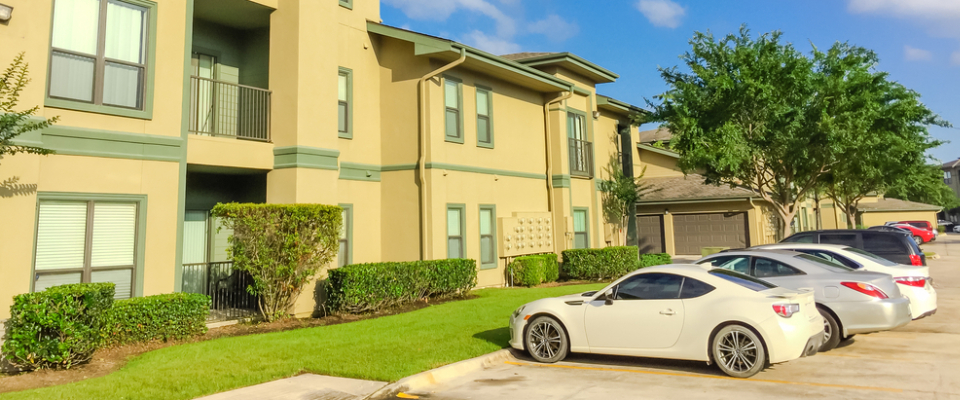 Apartment complex with parked cars in front, illustrating the importance of parking options and transportation access when renting apartments in Ann Arbor, MI.
