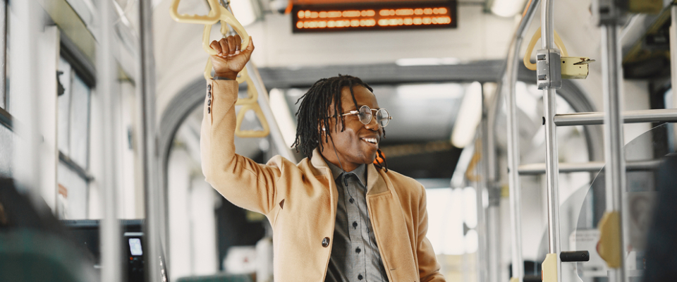 A smiling renter riding a Jacksonville public transit bus, holding a handrail while commuting comfortably through the city.