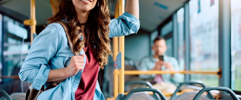 Young smiling woman riding a public bus, representing the convenience and accessibility of Sacramento public transit.