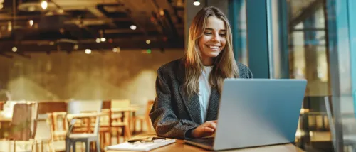 A woman using a laptop in a cafe to illustrate what is an online rental application.