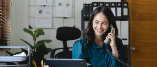 A person holding a wired phone while using a tablet to perform the duties of a property manager.