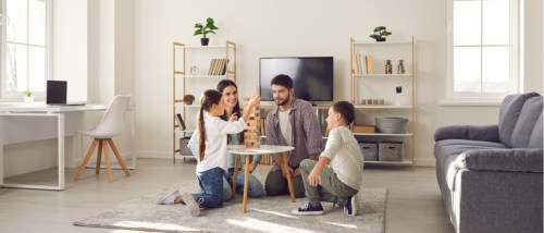 A family playing a game in the living room of their apartment to illustrate the best floor to live in an apartment with kids.