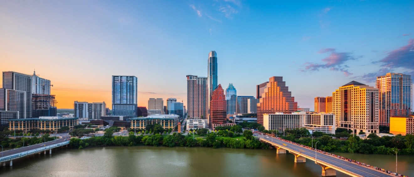 The skyline of Austin, TX, with a cloudy sky at sunset to illustrate the cost of living in Austin.