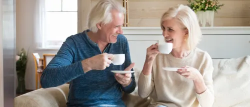 Smiling senior couple relaxing in their cozy home, reflecting on the benefits of decluttering and following downsizing tips for seniors.