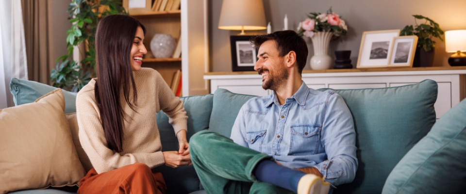 Young couple relaxing on a living room sofa, enjoying their time together before an upcoming apartment inspection.
